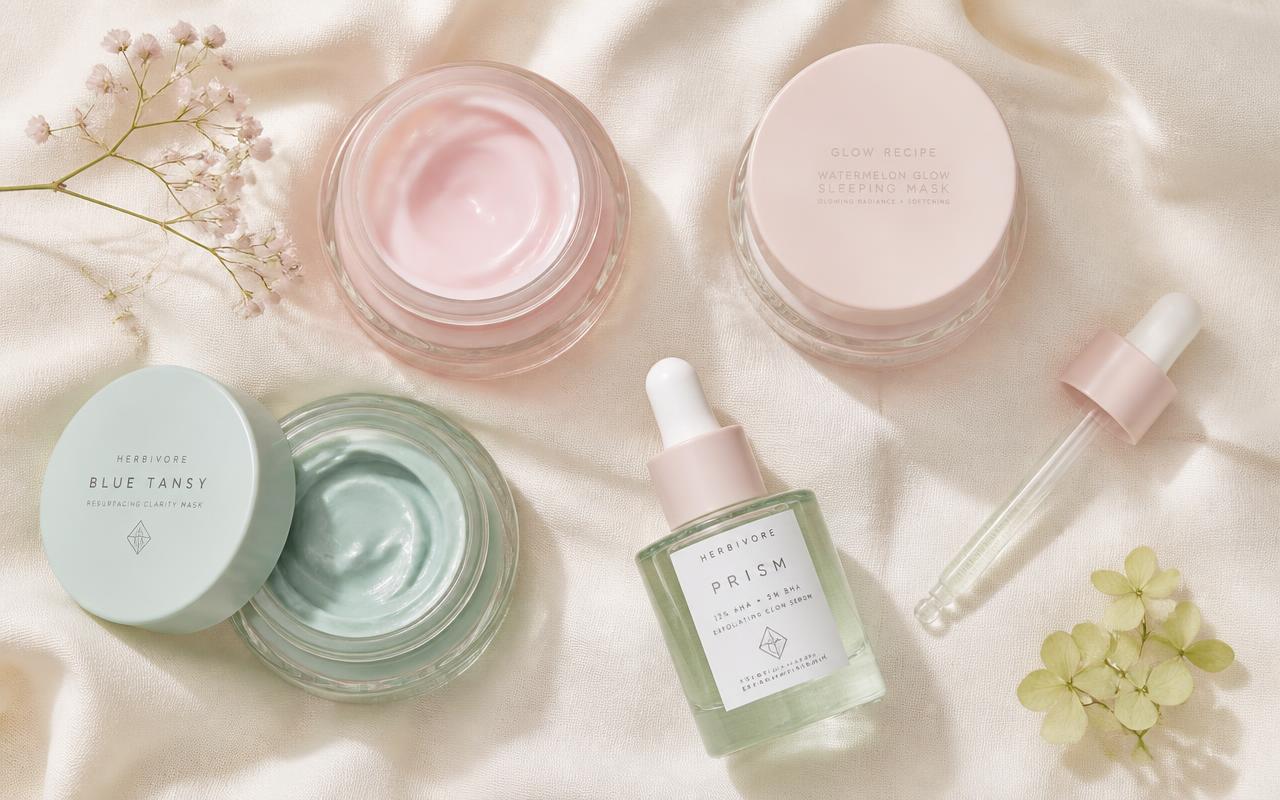 Flat lay of Glowskin glass jars and a dropper on cream textile